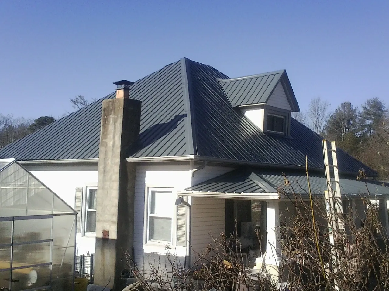 Dark blue standing seam metal roof on a white farmhouse with dormer — Slate & Tile Roof Repair by Roofing Brothers in Paisley