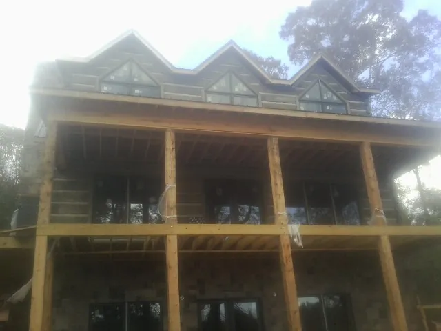 Dormers and porch framing on a large log home under construction — Roof Coating work by our crew in Paisley