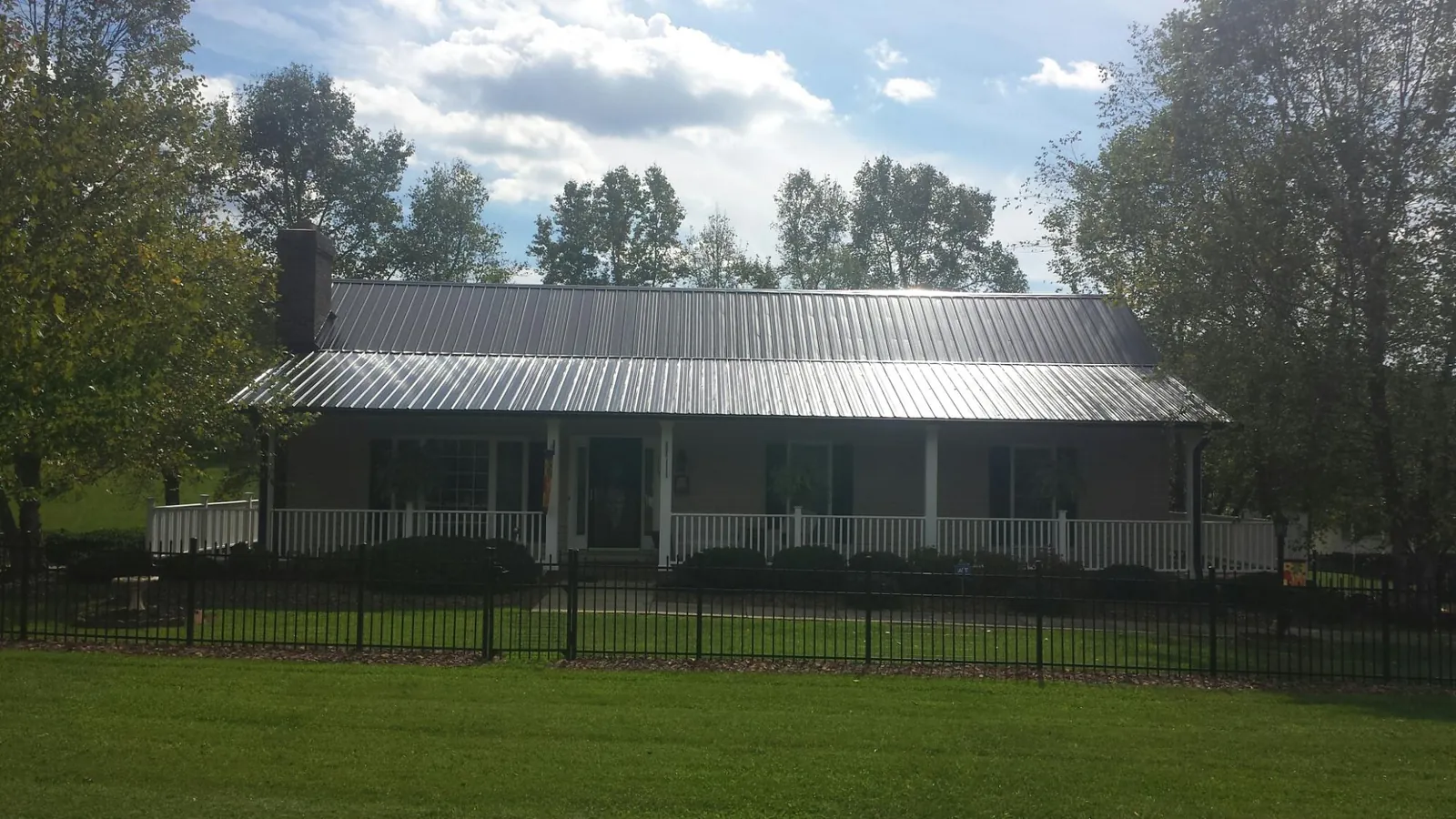 Gray metal roof on a brick ranch with a full width front porch — Gutter Guard Installation work by our crew in Paisley