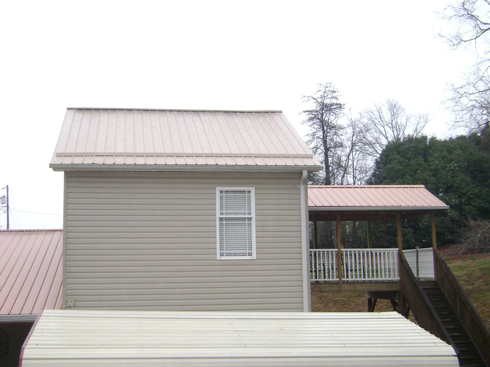 Tan metal roofs on a two story addition and attached porch, from a Roof Replacement job in Paisley