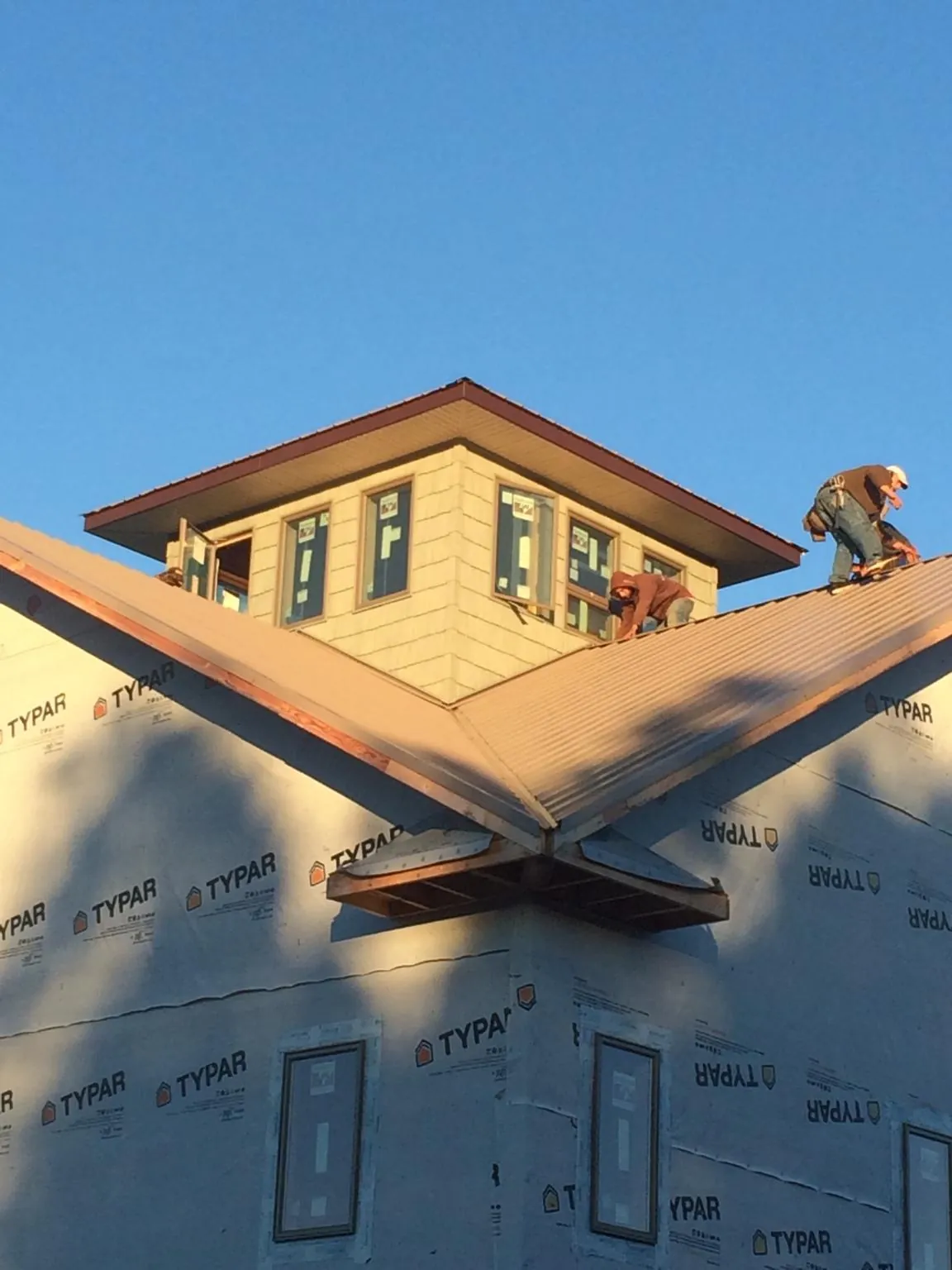 Roofers working around a rooftop cupola on a new metal roof at sunset — Roof Waterproofing in Paisley by Roofing Brothers